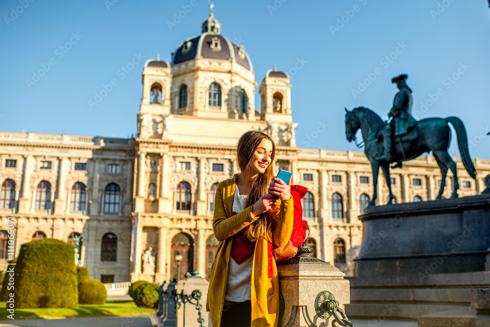 维也纳自然历史博物馆附近的玛丽亚·特蕾莎广场上年轻的女游客拿着智能手机
