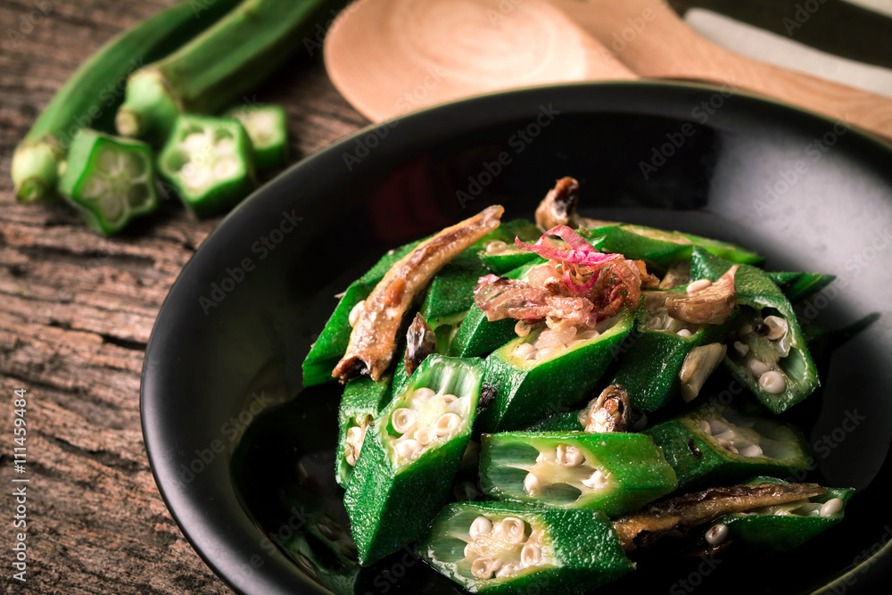 Stir Fried Okra with small fish Asian style on wooden surface in