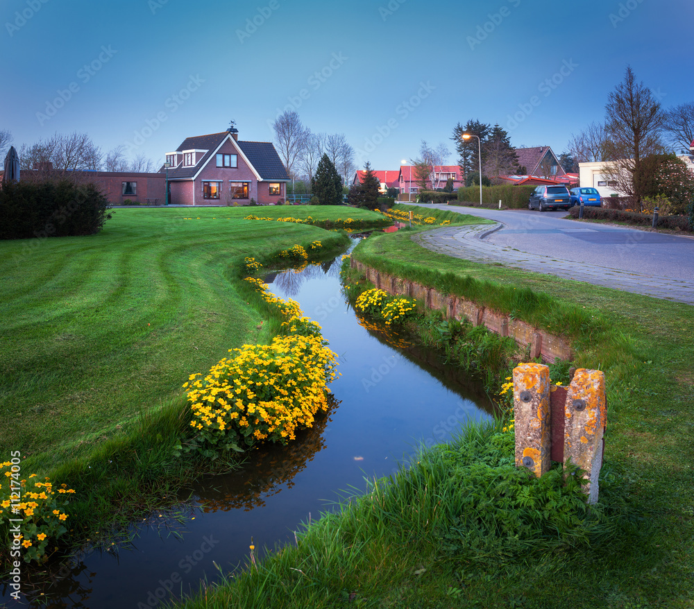 荷兰村庄的景观，美丽的房子倒映在运河中，庭院绿草如茵
