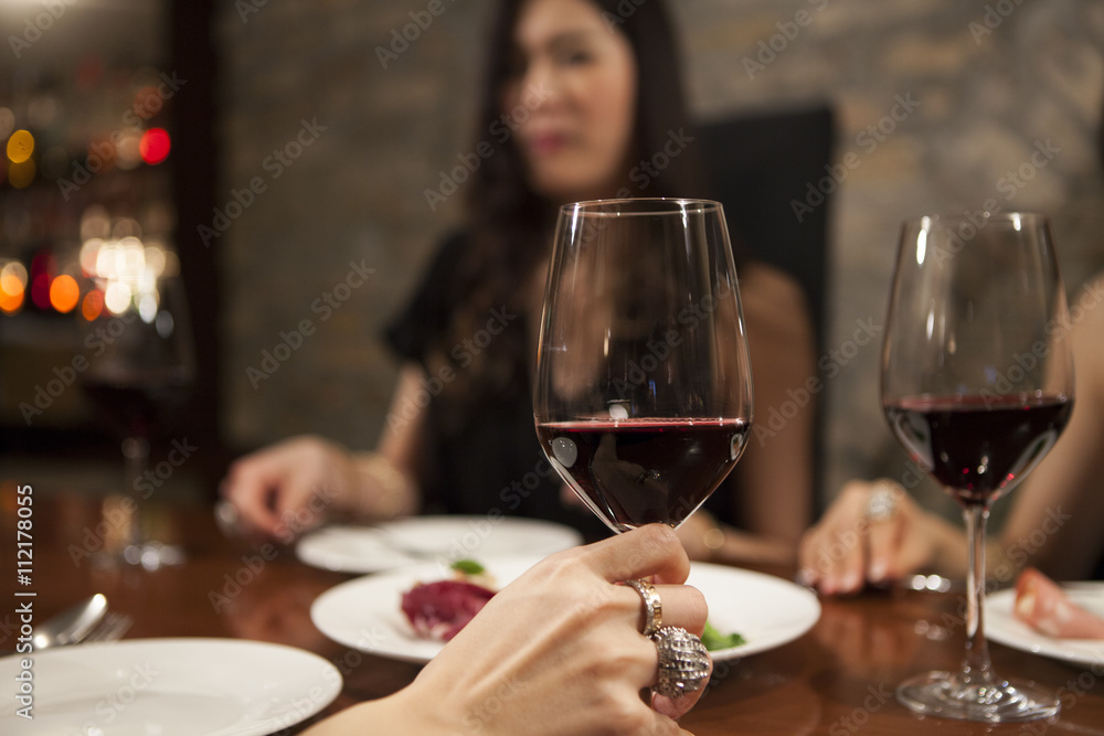年轻女性正在用一杯葡萄酒享受这顿饭
