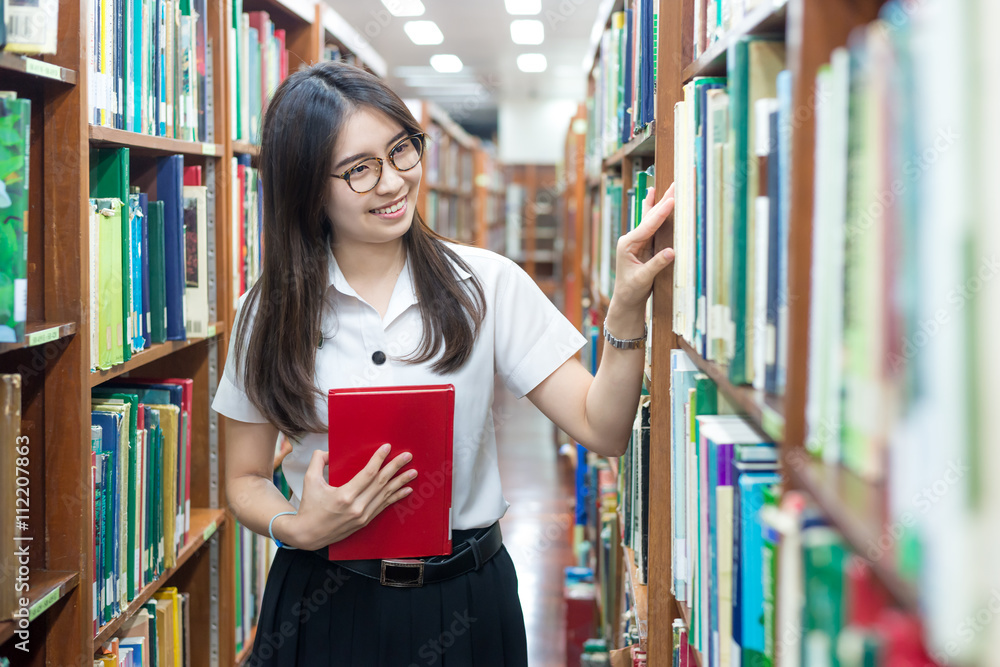 穿着制服的亚洲学生在大学图书馆阅读