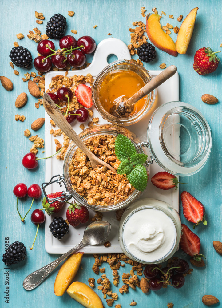健康早餐原料。开放式玻璃罐燕麦格兰诺拉麦片、酸奶、水果、浆果、蜂蜜和薄荷