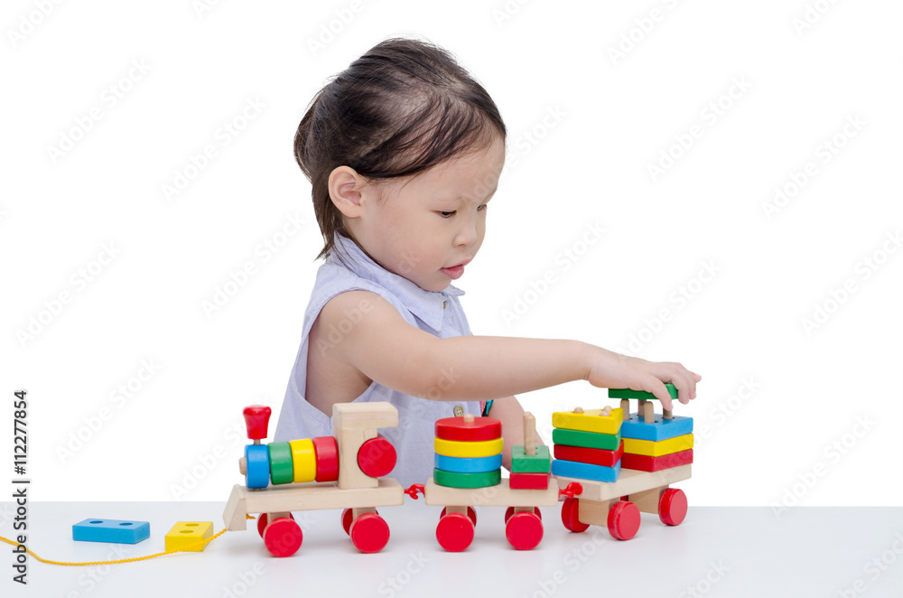 亚洲小女孩在白色衣服上玩木制火车玩具