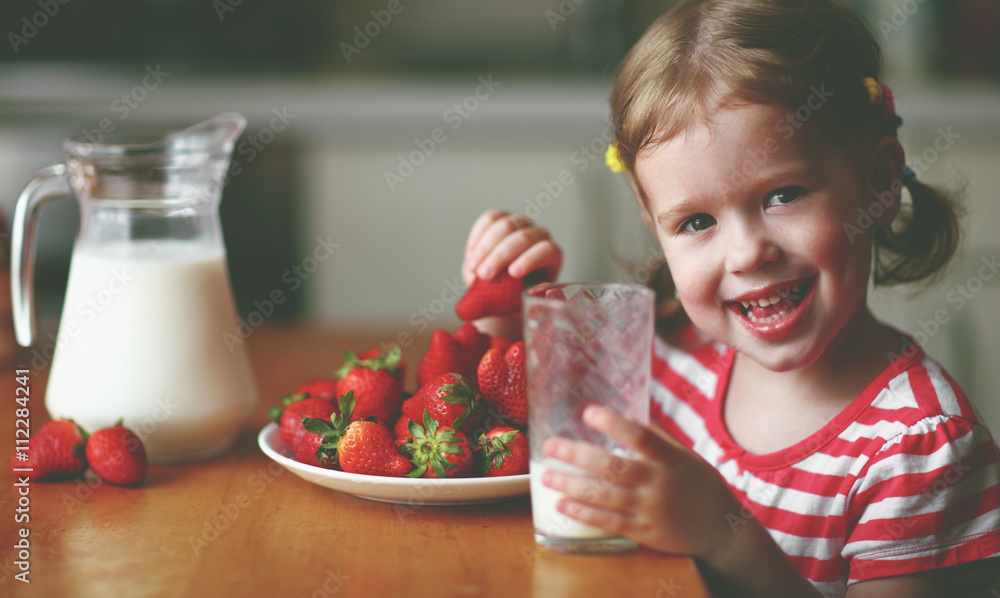 快乐的小女孩在夏天喝牛奶吃草莓