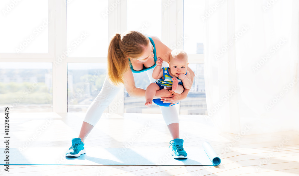 sports mother is engaged in fitness and yoga with baby at home