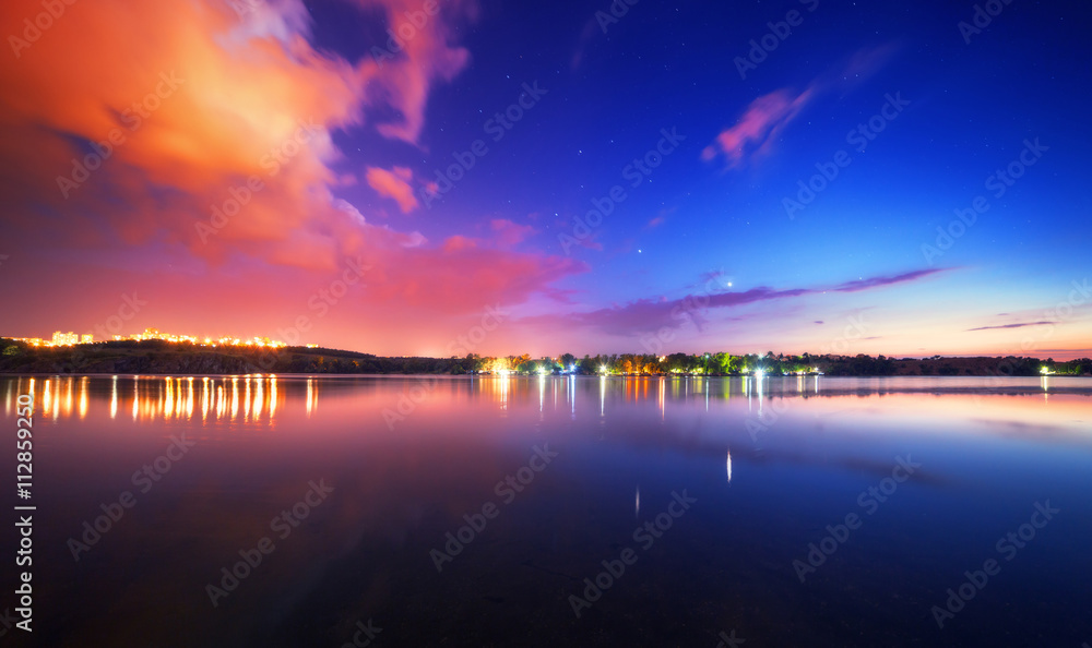 湖面上色彩缤纷的夜景，蓝天白云映水中。大自然回来了