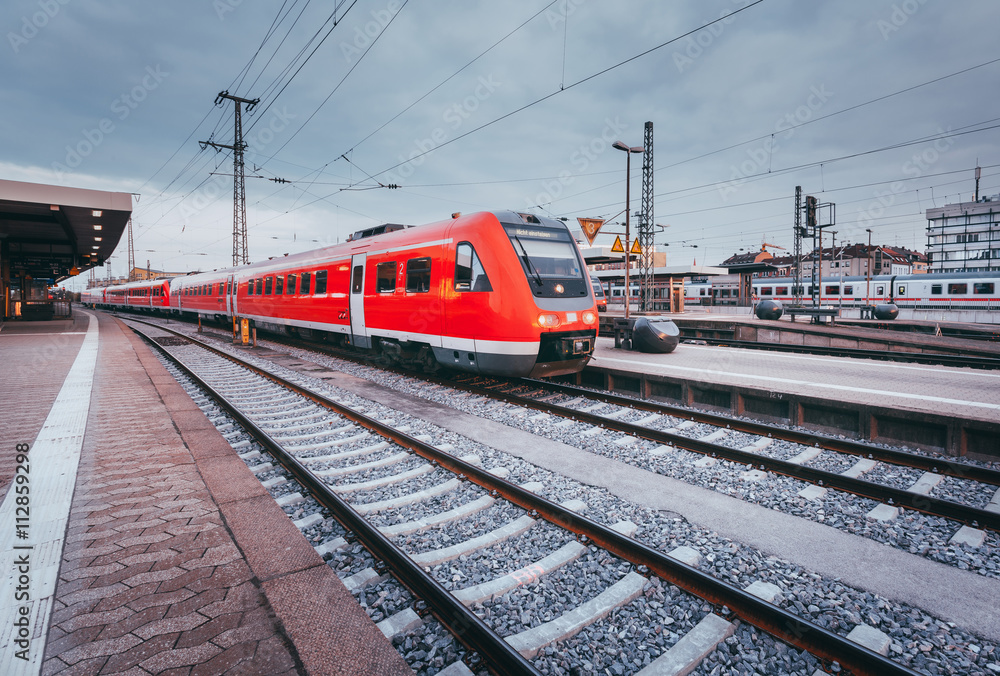 德国纽伦堡日落时分的火车站，有现代化的红色客运列车。有文塔的铁路