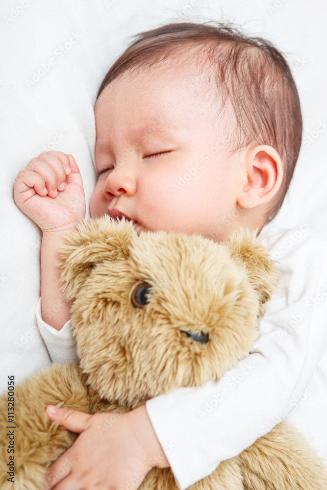 Newborn sleeping with her teddy bear, new family and love concep