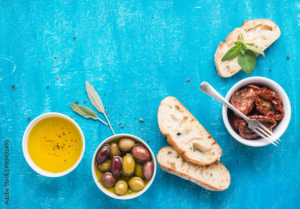 地中海小吃套装。橄榄、油、晒干的西红柿、香草和切好的ciabatta面包。