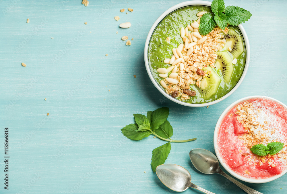 健康的夏季早餐概念。绿松石蓝色背景的彩色水果奶昔碗