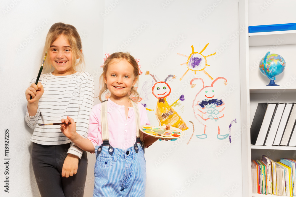 两个快乐的女孩在墙上画有趣的画