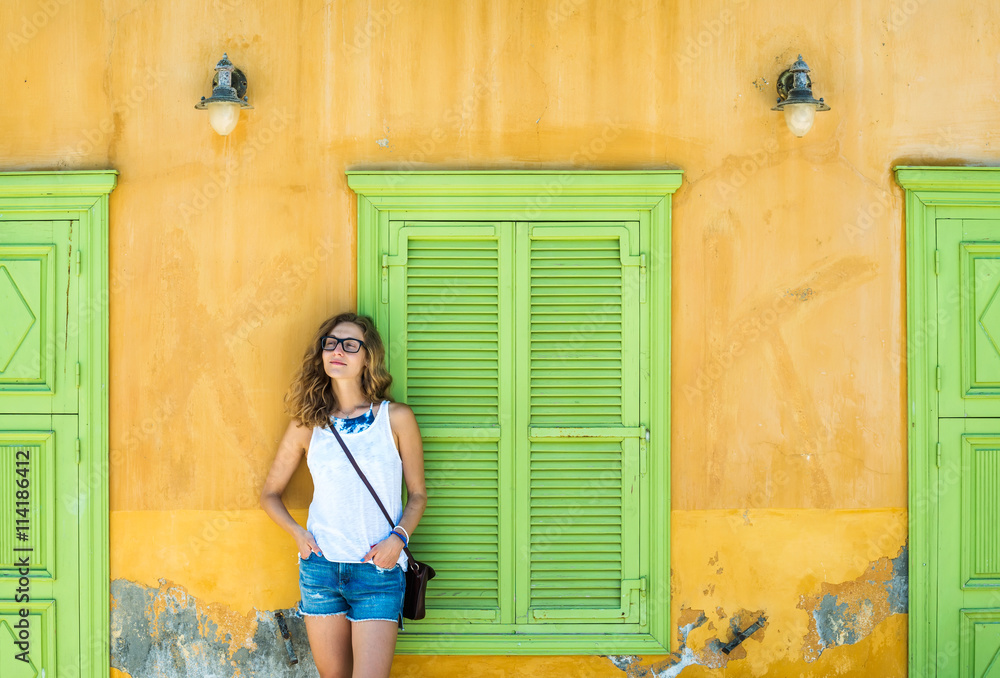 希腊卡斯特洛里佐岛上一个典型的希腊小镇上的年轻金发女人，那里有五颜六色的建筑