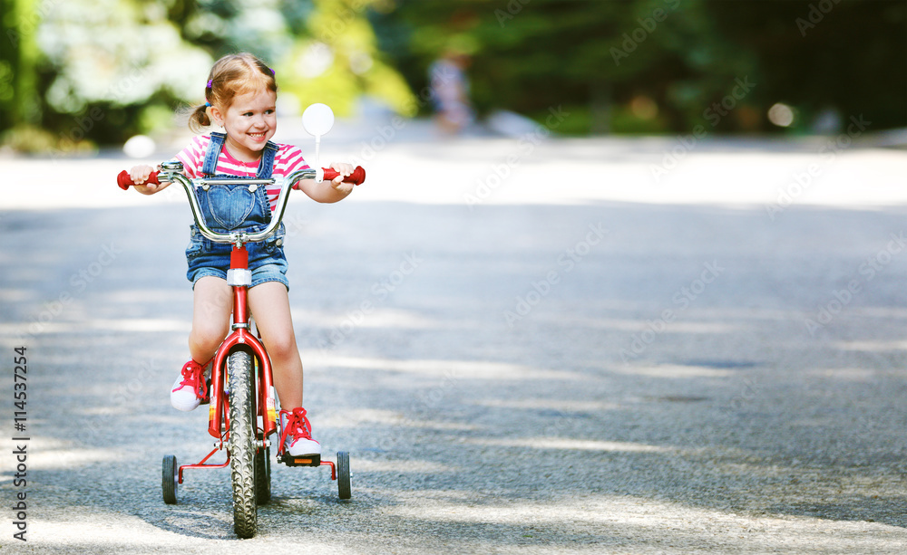 happy child girl cyclist riding a bike