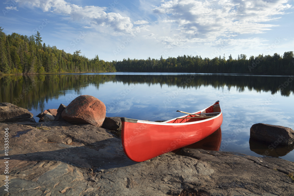 平静的松树湖岩石岸边的红色独木舟