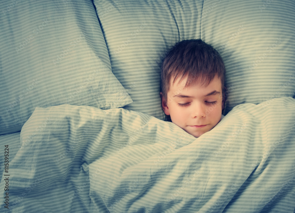 seven years old child lying in the bed with blue bedding