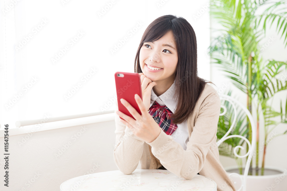 亚洲女学生在咖啡馆使用智能手机