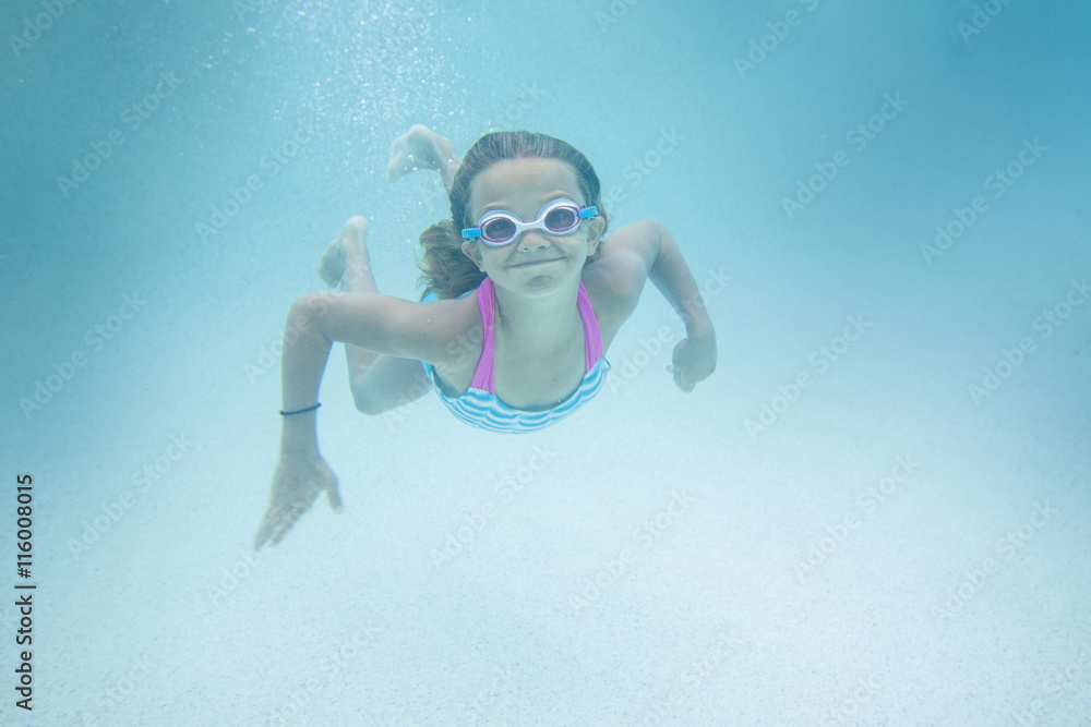 可爱的微笑小女孩在户外游泳池的水下游泳