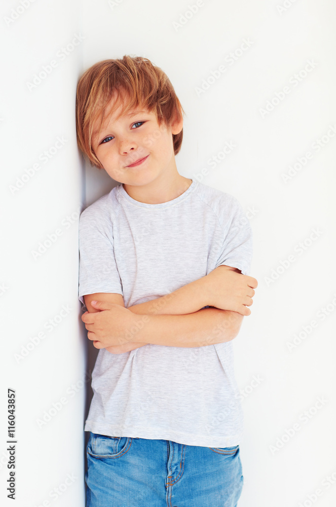 英俊的小男孩，在白墙附近摆姿势的孩子