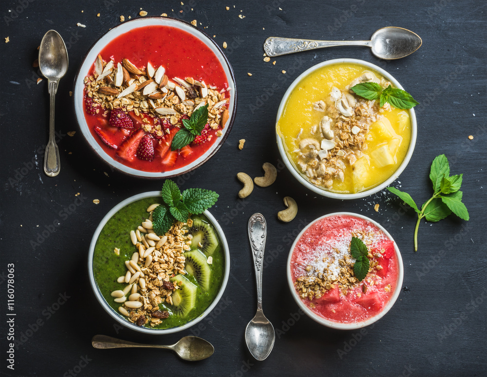 健康的夏季早餐概念。五颜六色的水果奶昔碗，配坚果、燕麦格兰诺拉麦片和薄荷叶