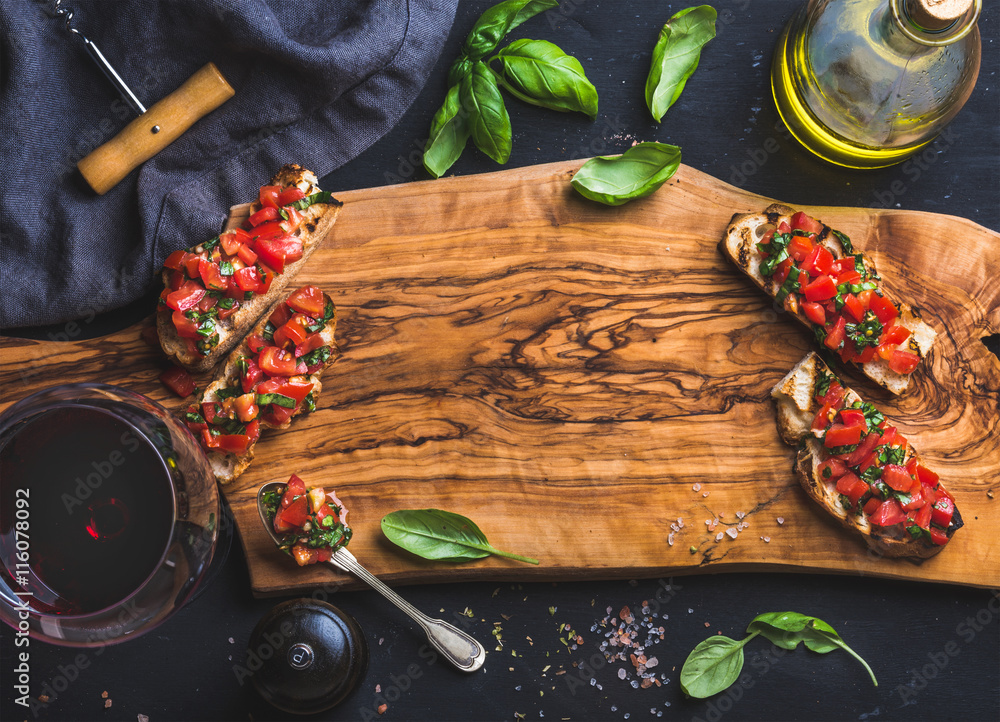 番茄和罗勒肉排配一杯红酒、橄榄油、盐、新鲜香草在木板上