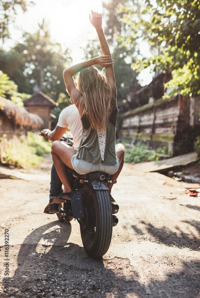 Young couple riding motorcycle on rural road