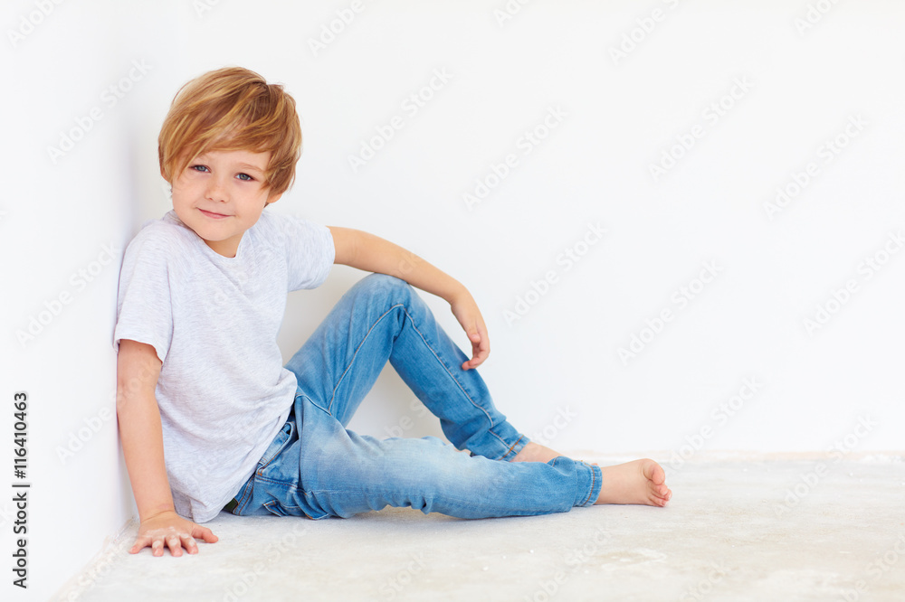 英俊的小男孩，坐在白墙上的孩子