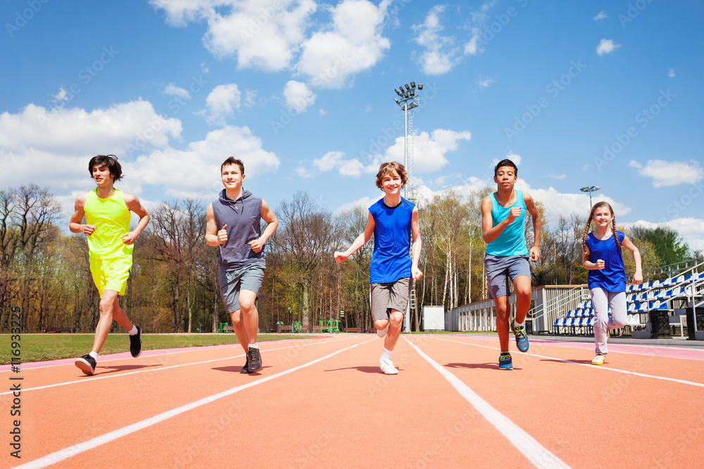 五名青少年短跑运动员一起在跑道上奔跑