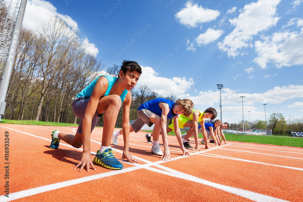 五名青少年运动员准备在跑道上奔跑