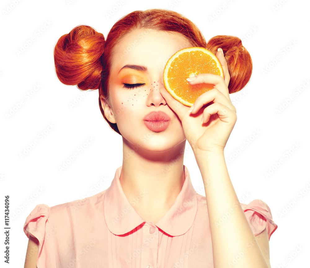 Beautiful joyful teen girl with freckles holding juicy orange slice