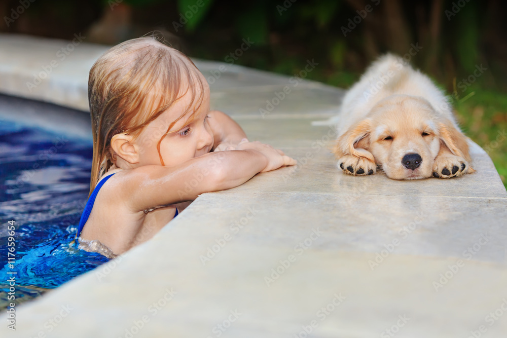 小婴儿在蓝色室外游泳池游泳的有趣照片，看着一只懒洋洋的寻回犬。孩子们在看