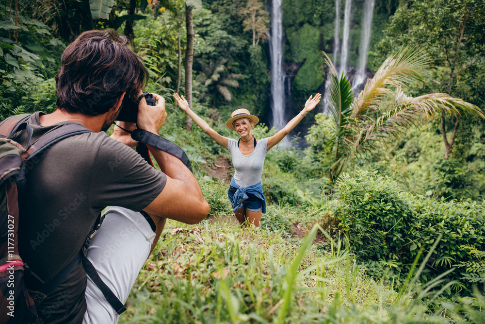 摄影师在瀑布边给一个女人拍照