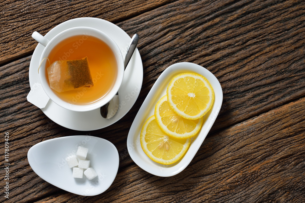 一杯茶的俯视图，木桌上有茶包、方糖和柠檬