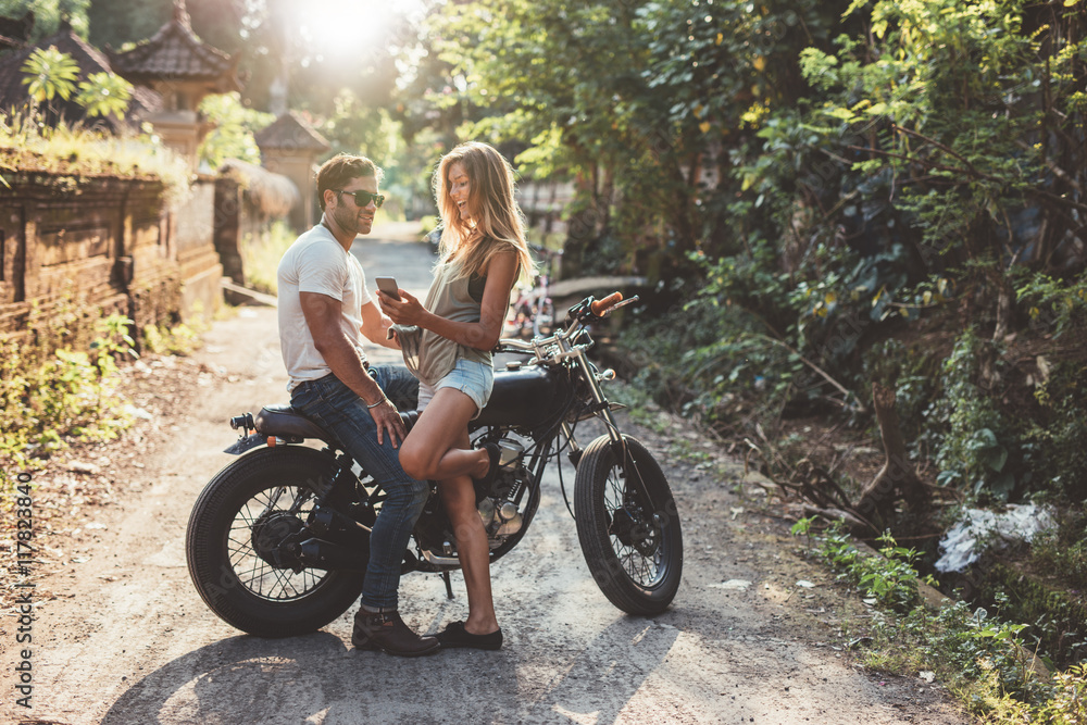 一对年轻夫妇骑着摩托车在乡间小路上欢欢喜喜