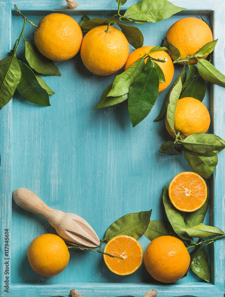 带叶子的新鲜橙子，用于在蓝色涂漆的木质背景上制作果汁，俯视图，复制空间，