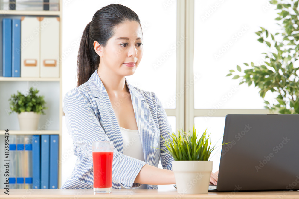 商务女性用电脑喝新鲜西瓜汁