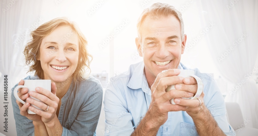 微笑的中年夫妇坐在沙发上喝咖啡