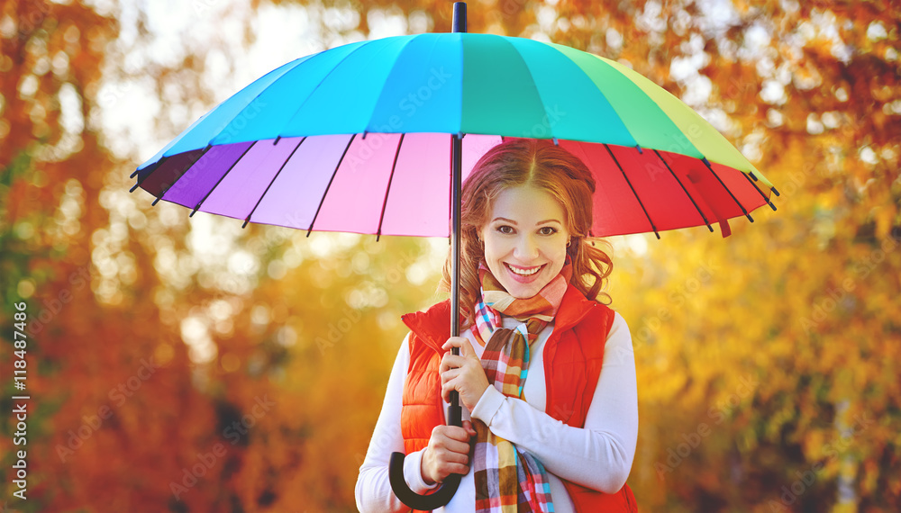 happy woman with rainbow multicolored umbrella under rain in par
