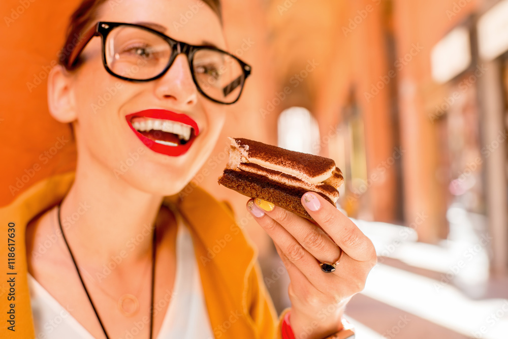 一名年轻女子在意大利博洛尼亚市的街道上吃意大利传统甜点提拉米苏。Ti