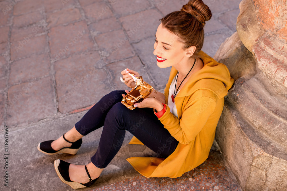 一名年轻女子在意大利博洛尼亚市的街道上吃意大利传统甜点提拉米苏。Ti