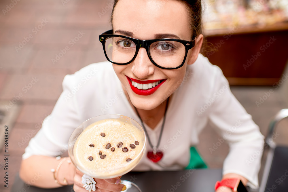 一位年轻女士坐在咖啡馆里，在户外的鸡尾酒杯里喝着沙卡拉托饮料。传统意大利语