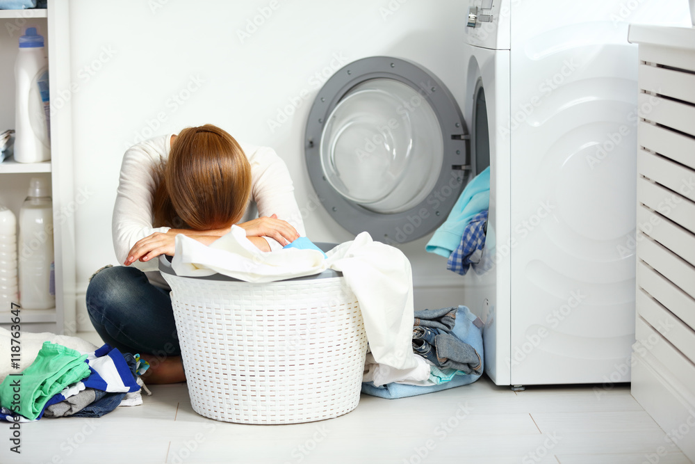 疲惫不快乐的女人家庭主妇把衣服叠到洗衣机里