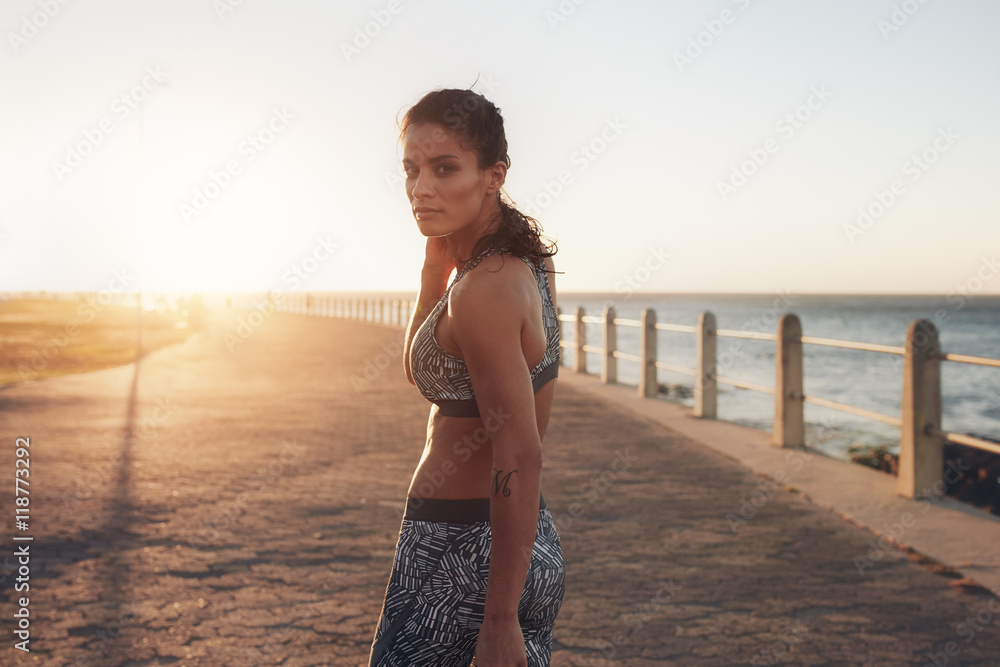 穿着运动服在海边行走的肌肉发达的年轻女子