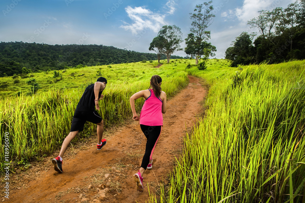 情侣跑步者在大自然中慢跑，以更快的速度爬上更高的山