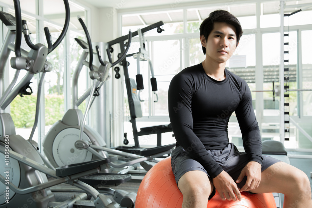 亚洲男子坐在健身房