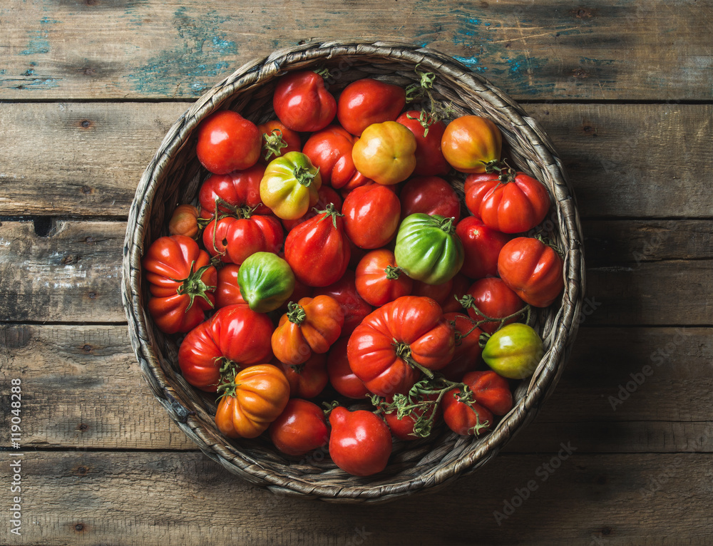 木制背景下篮子里的新鲜彩色成熟秋季传家宝番茄，俯视图，水平co