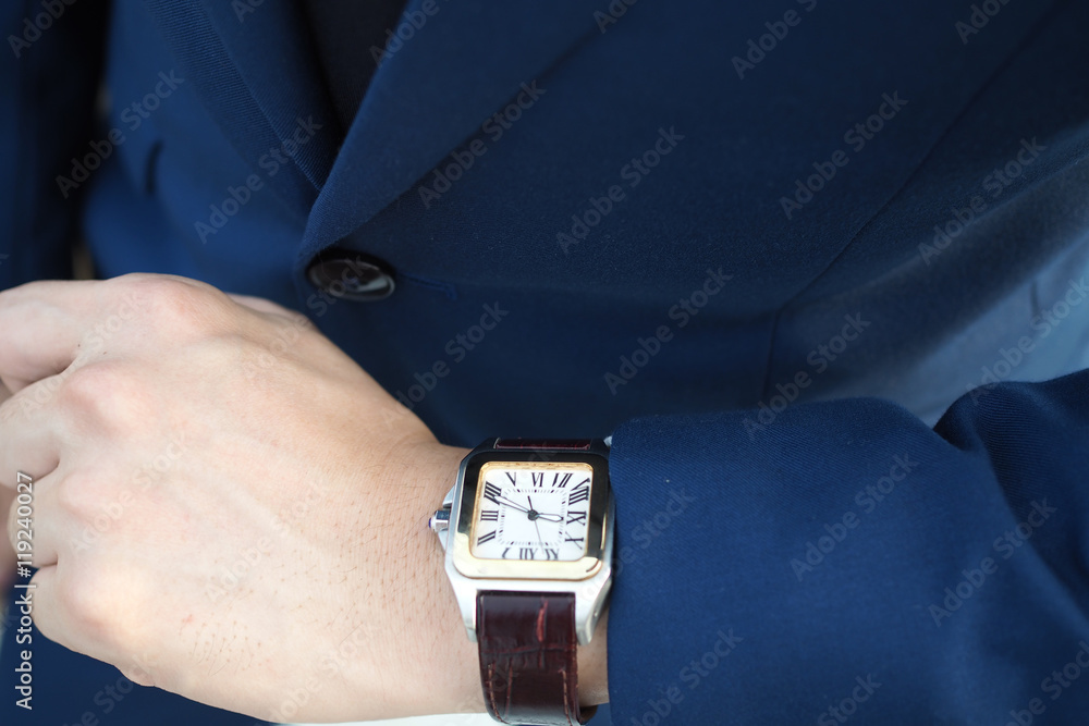 穿着优雅蓝色西装的商人看着等待的豪华手表