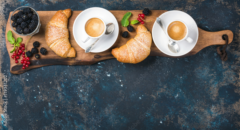 Breakfast set. Freshly baked croissants with garden berries and coffee cups served on rustic wooden 