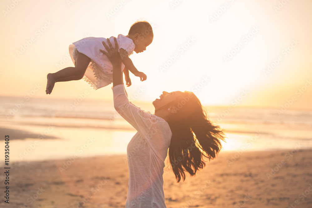 日落时海滩上的母亲和婴儿肖像