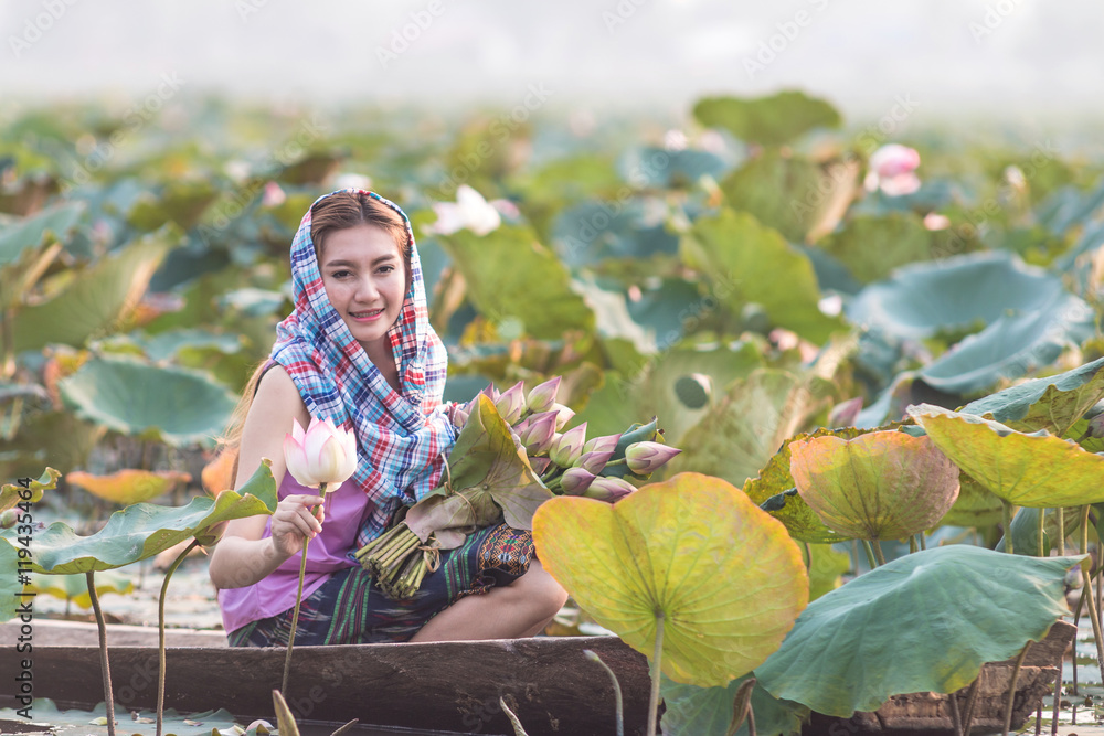Rural girl sitting in boat in the lotus field.