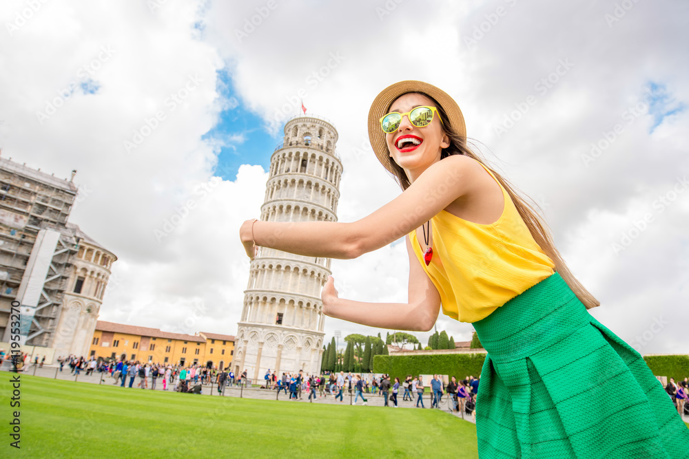 年轻的女旅行者在意大利比萨古城著名的斜塔前玩得很开心。Hap